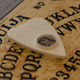 An Ouija board, the pointer resting over the T.